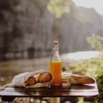 Vue du petit-déjeuner sur le ponton avec le lever du soleil, jus d'orange, croissants, pain et yaourt - Parenthèse Flottante