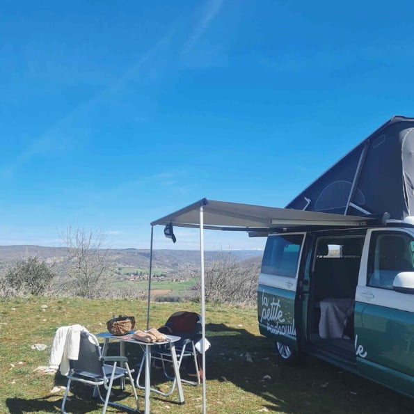 Photo du Van avec le toit ouvert sur un spot pour admirer la vue - table pour les repas est ouverte et mise en place - ma petite vadrouille