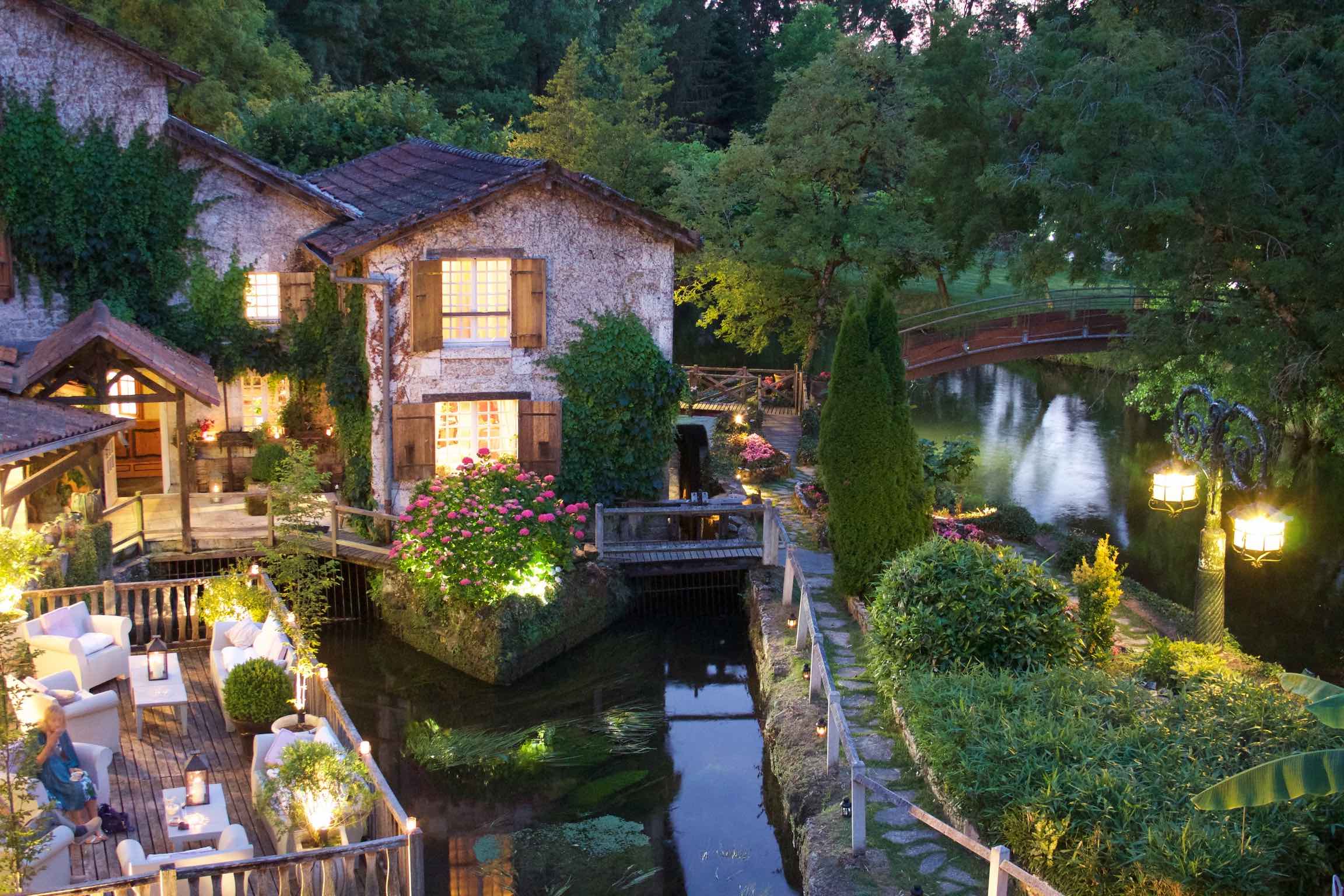 Hôtel Moulin du Roc vue de loin avec la rivière et les lumières allumées