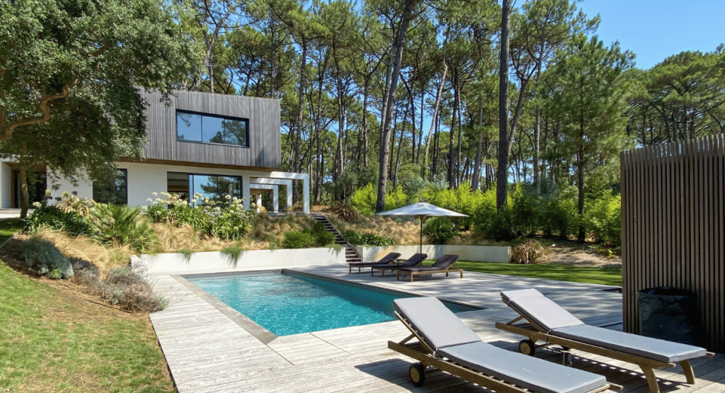 Transat au cord d'une piscine et en fond la villa Landifornia et ses baie vitrées