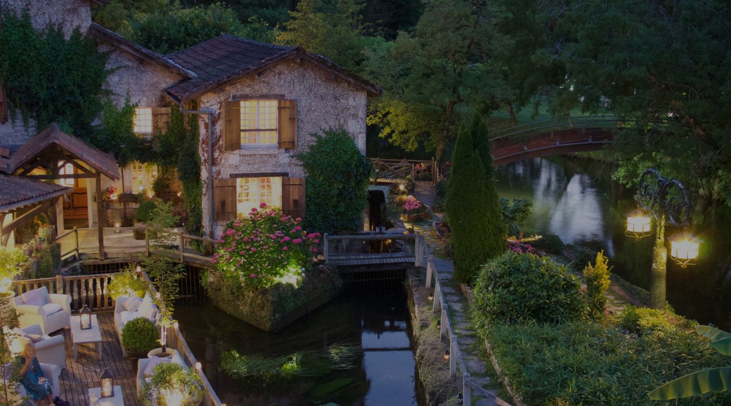 Hôtel Moulin du Roc vue de loin avec la rivière et les lumières allumées