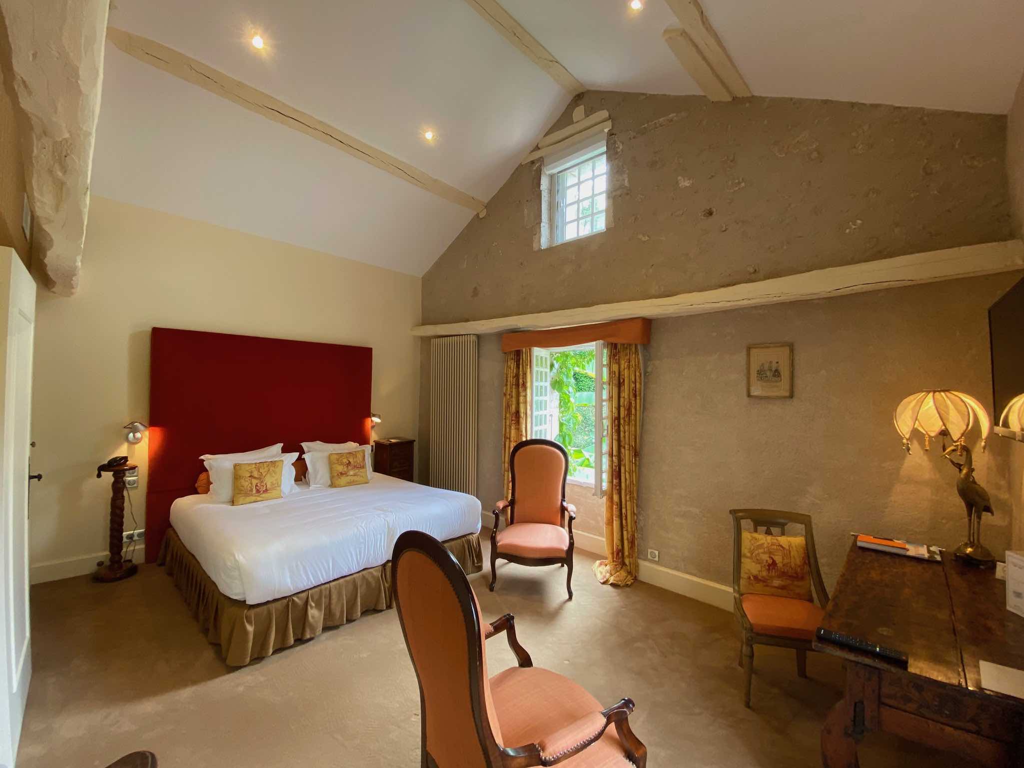 chambre avec lit double fauteuils fenêtres ouvertes