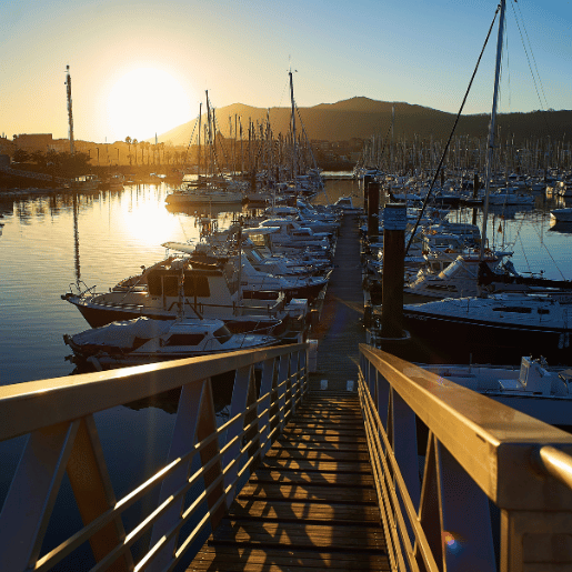 Ponton qui mènent vers les voiliers du port avec une coucher de soleil en fond