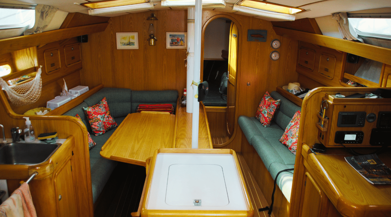 intérieur de la cabine d'un voilier. Table au centre et canapé deux deux côtés avec cuisine équipé à gauche