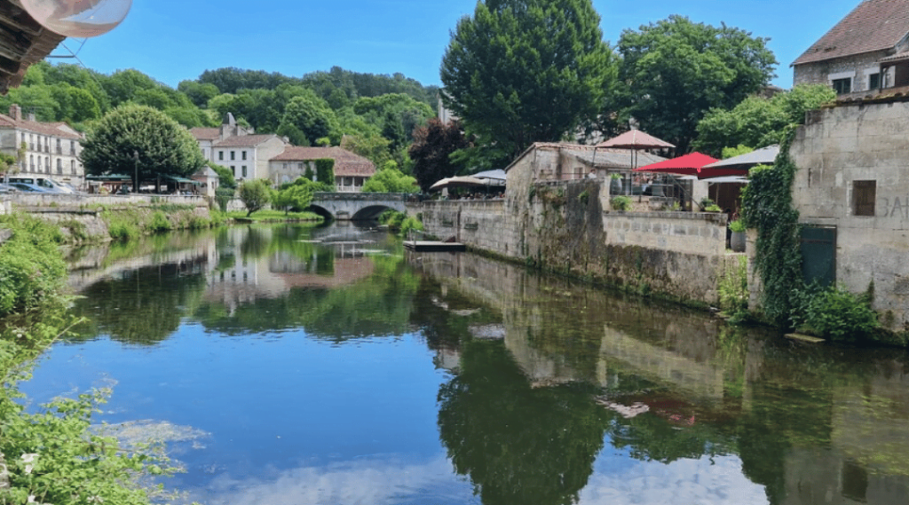 rivière avec pont en fond et maison en pierre en fond de l'image