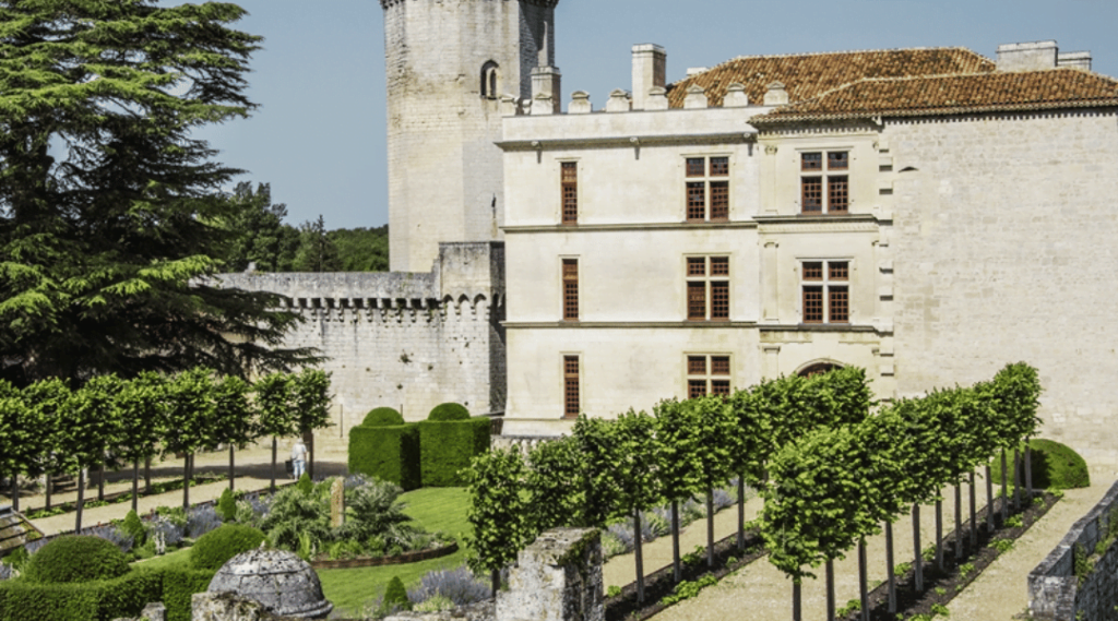 jardin avec deux allée d'arbres face à un chateau